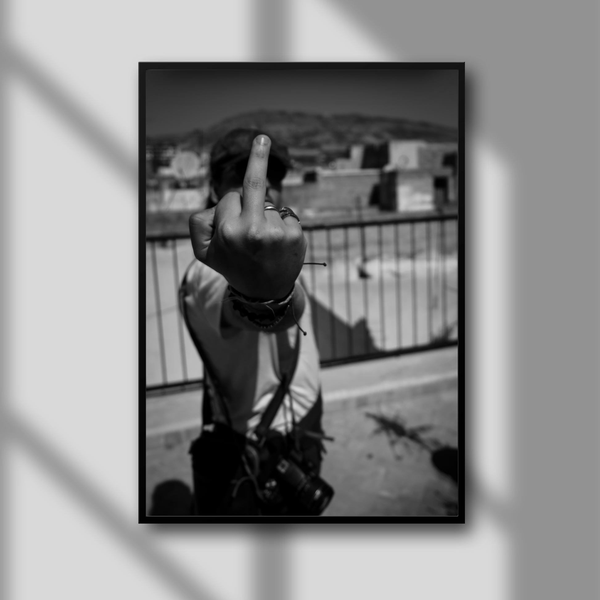 This image presents a bold and provocative artwork titled "F*** That," which features a striking black and white photograph. The picture captures a moment of rebellion, showing a person giving a middle finger to the camera from a rooftop vantage point, set against a backdrop of a large tannery.