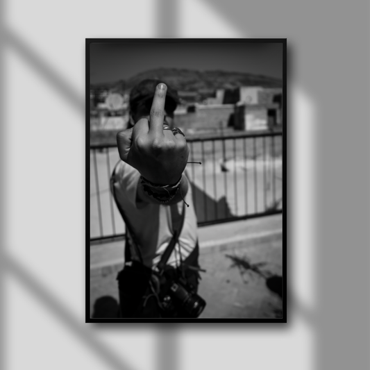 This image presents a bold and provocative artwork titled "F*** That," which features a striking black and white photograph. The picture captures a moment of rebellion, showing a person giving a middle finger to the camera from a rooftop vantage point, set against a backdrop of a large tannery.